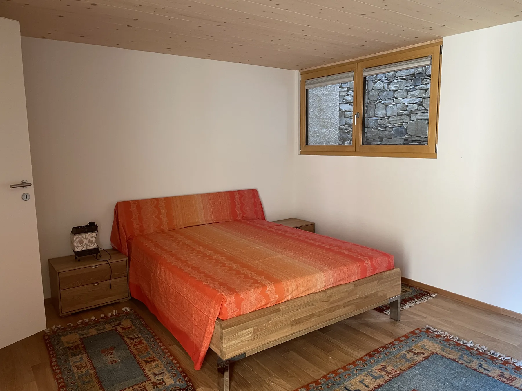 Camera matrimoniale con pareti chiare e soffitto in legno